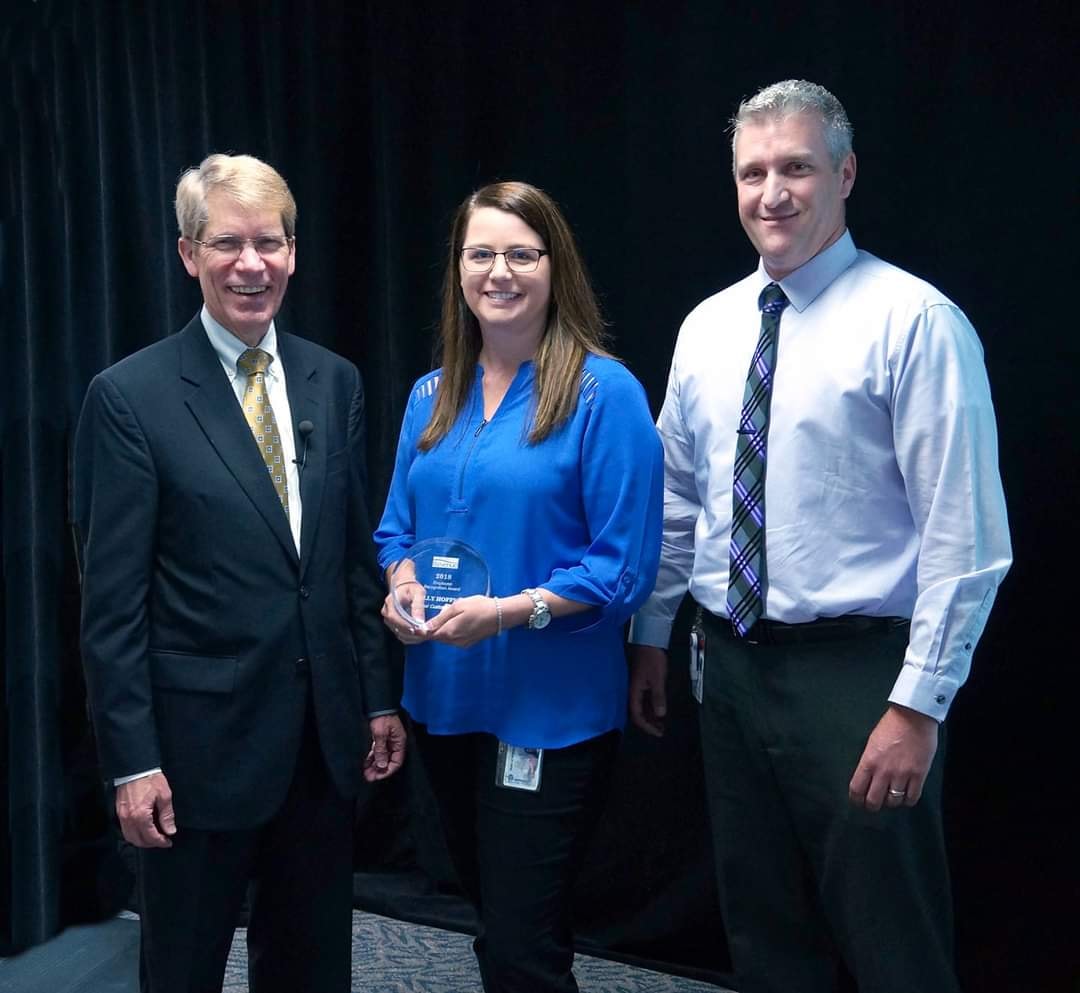 Holly receiving an award flanked by two colleagues at a professional ceremony